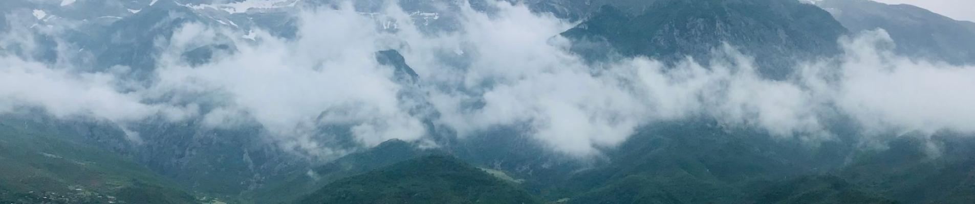 Stunning view of lush valleys and cloud-covered mountains in Përmet, Albania.