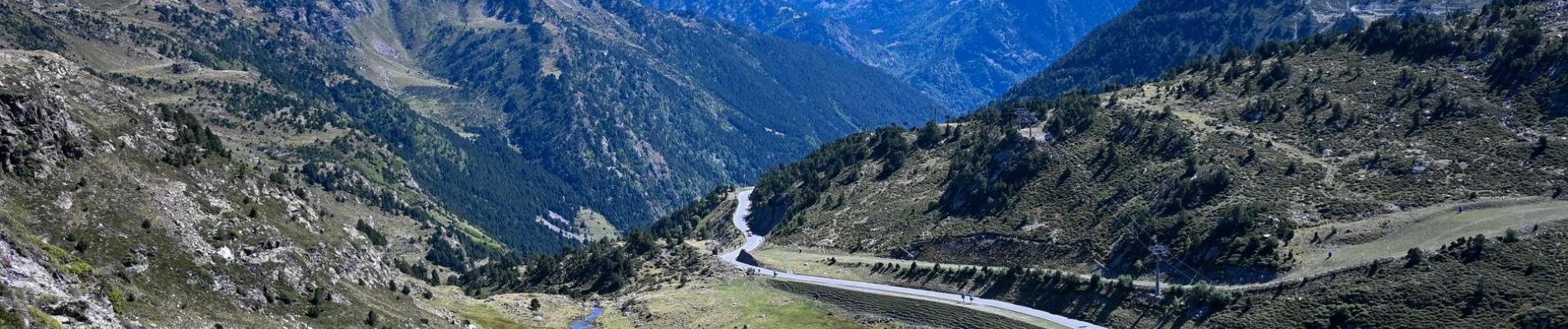 Aerial view of a winding road cutting through the lush Pyrenees mountains.