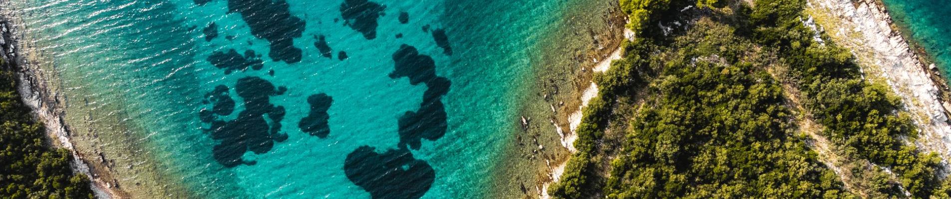 Stunning aerial shot of Croatia's coastline with clear turquoise waters and lush greenery.