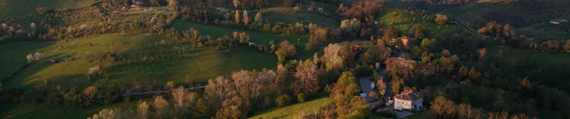 Stunning aerial view of the rolling hills and lush greenery of the Tuscan countryside at sunset.