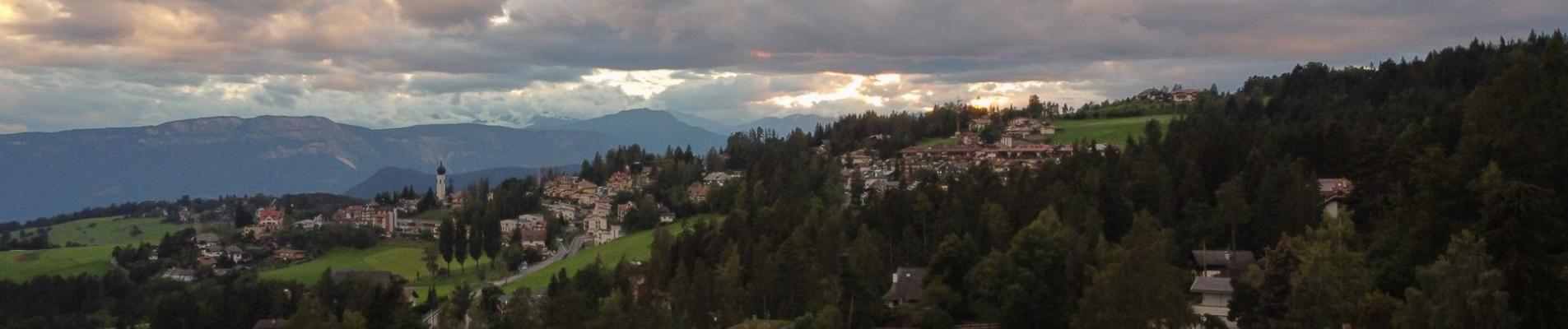 A picturesque landscape of Trentino-Südtirol with rolling hills and quaint houses.