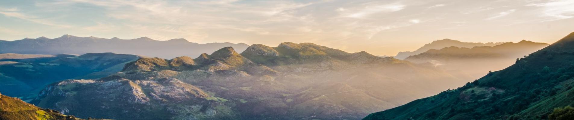Breathtaking mountain landscape in Spain captured during golden hour, featuring lush greenery and a clear blue sky.