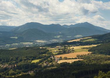 Panoramic view of Ternitz, Austria showcasing rolling hills and expansive mountain ranges under a cloudy sky.