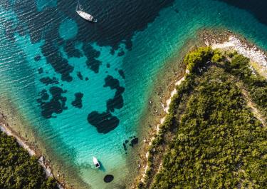 Stunning aerial shot of Croatia's coastline with clear turquoise waters and lush greenery.