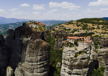 Stunning aerial shot of Meteora monasteries perched on rocky cliffs in Greece's landscape.