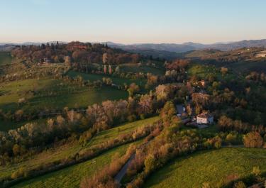 Stunning aerial view of the rolling hills and lush greenery of the Tuscan countryside at sunset.