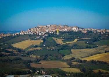 A picturesque hilltop town in Italy surrounded by lush green fields and vibrant landscapes.