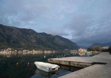 Peaceful morning view of Kotor Bay in Montenegro, showcasing calm waters and mountainous backdrop.