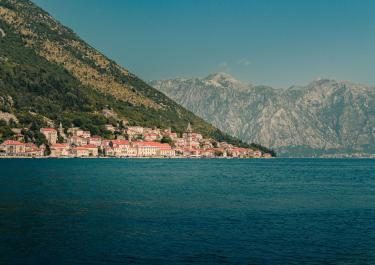 Panoramic view of a coastal town in Montenegro with mountains and sea.