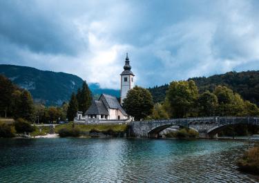 Picturesque view of St. John the Baptist Church and bridge over Lake Bohinj in Slovenia.