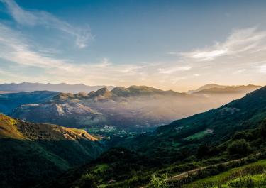 Breathtaking mountain landscape in Spain captured during golden hour, featuring lush greenery and a clear blue sky.